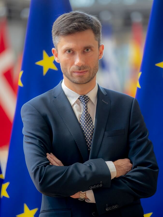 Filip Grzegorzewski na tle flag Unii europejskiej